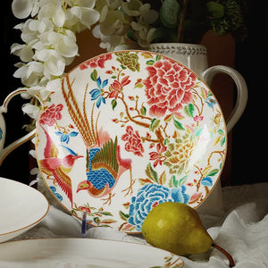 Two 9’’ round bone china salad plates upright with white floral decor and a pear.