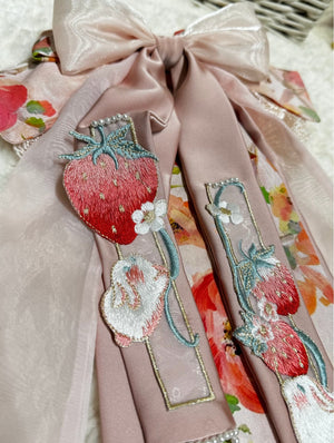 Close-up of strawberry and rabbit embroidery on soft pink brocade bow hair clip detail
