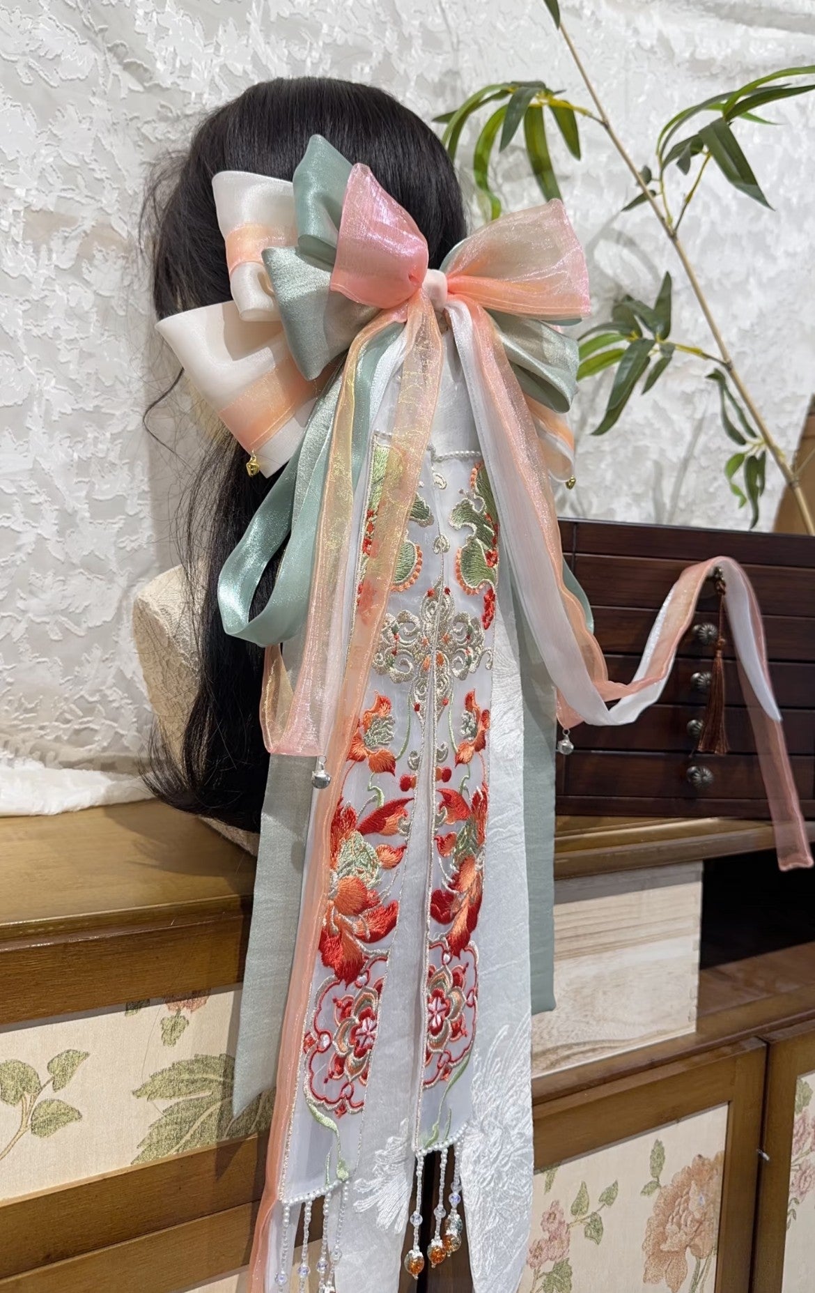 Side view of Dream of Dunhuang new Chinese hair bow with layered orange green ribbons