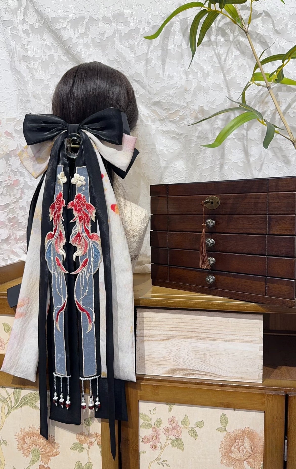 Side view of Black Koi bow hair accessory with flowing ribbon tails and statement shape