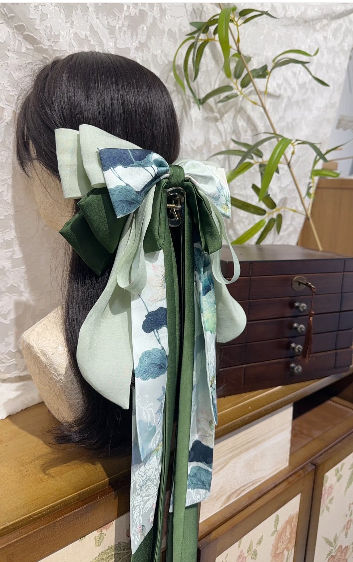 Side view of Green Lotus oversized bow hair clip with layered ribbons and elegant drape