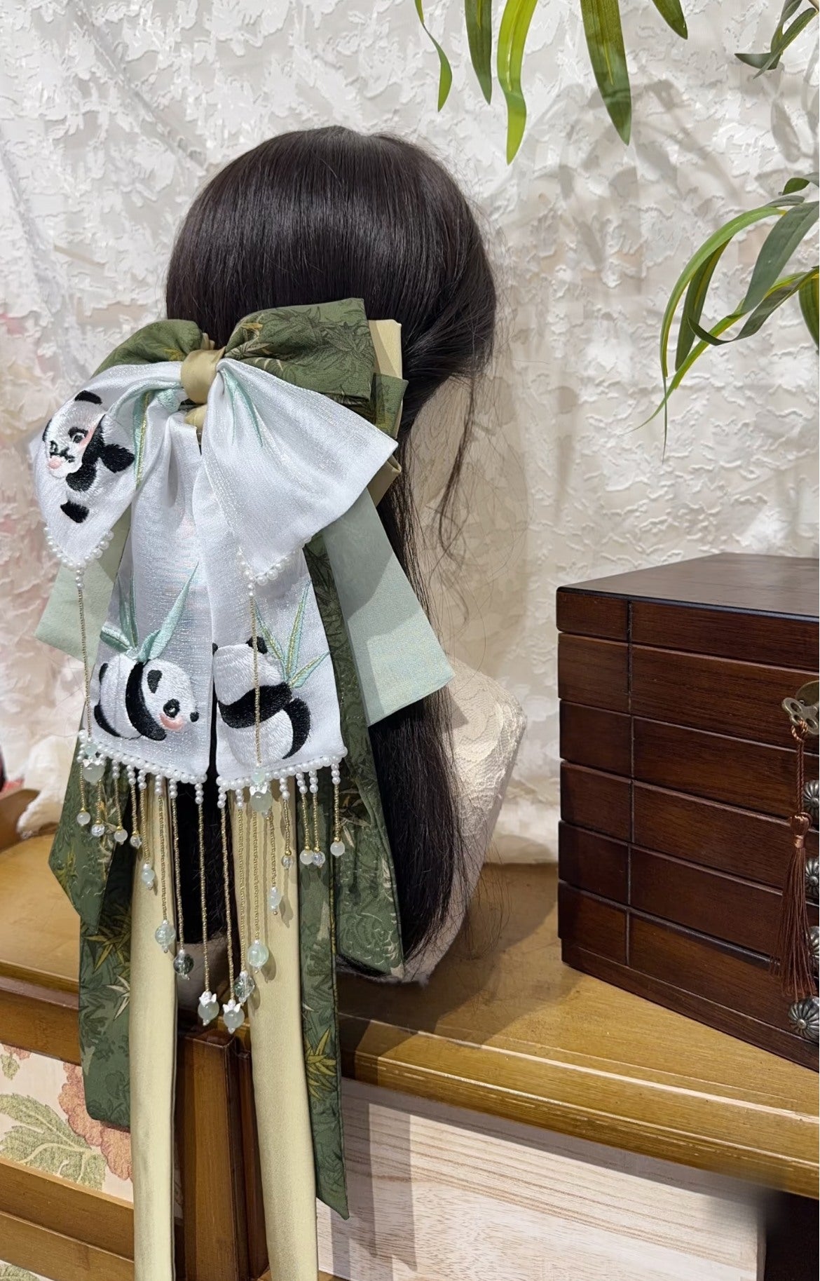 Side detail of Panda Firecracker bow hair accessory with green ribbons and festive embroidery