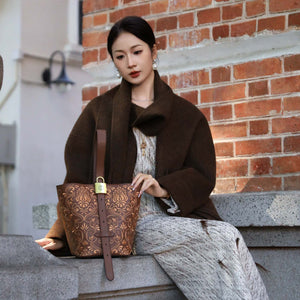 Close view of embroidered bucket bag showing floral texture and refined leather finish featuring Dunhuang Scroll Grass