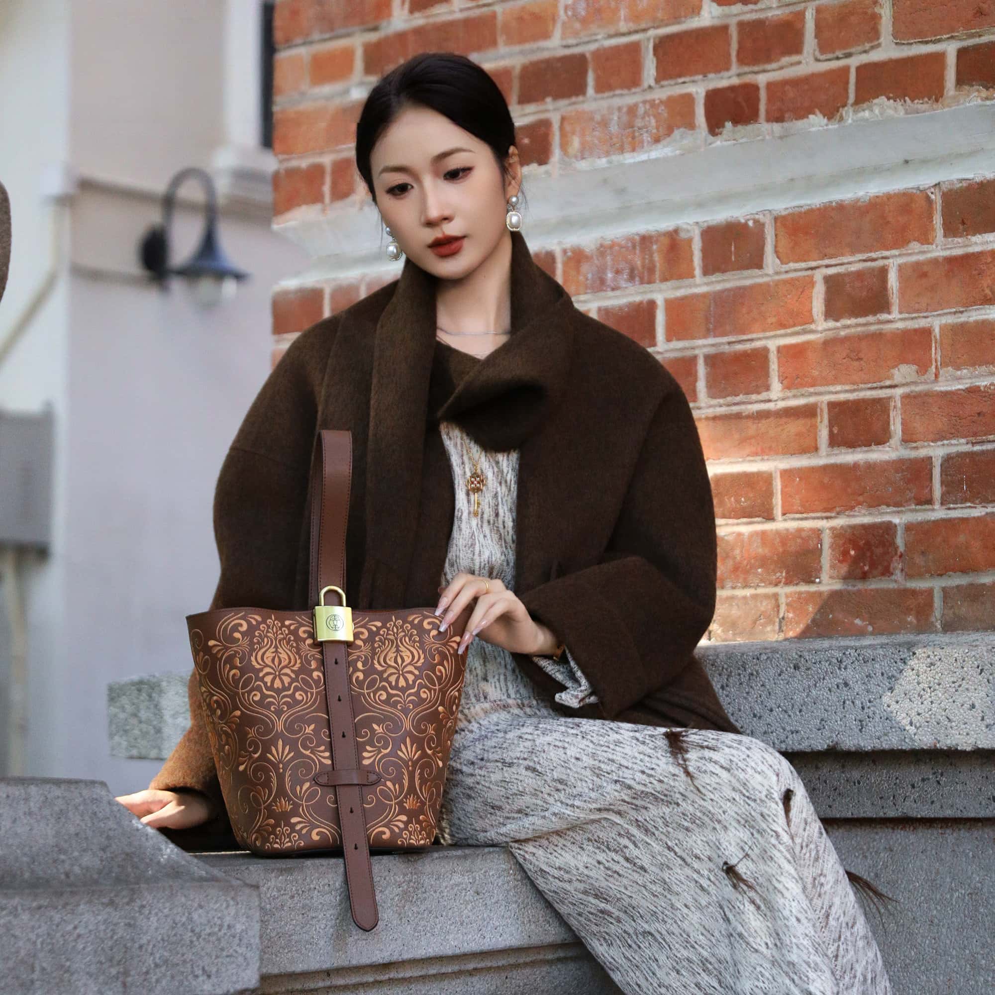 Close view of embroidered bucket bag showing floral texture and refined leather finish featuring Dunhuang Scroll Grass