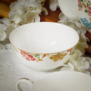 Chinoiserie bone china round bowl on table with floral background (angled view).