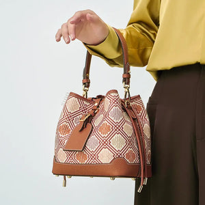 Model carrying bucket bag in arm crook position.