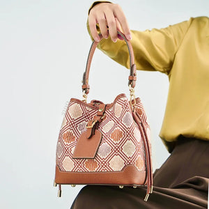 Seated model holding brocade bucket bag on knees.