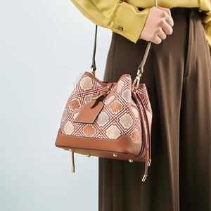 Model wearing brocade bucket bag on shoulder.