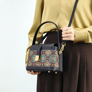 Model wearing crossbody bag with scrolling foliage motif.