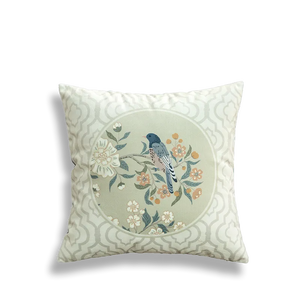 White embroidered pillow with circular birds and flowers.