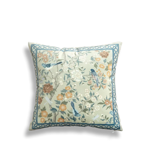 White embroidered pillow featuring full floral and bird scene.