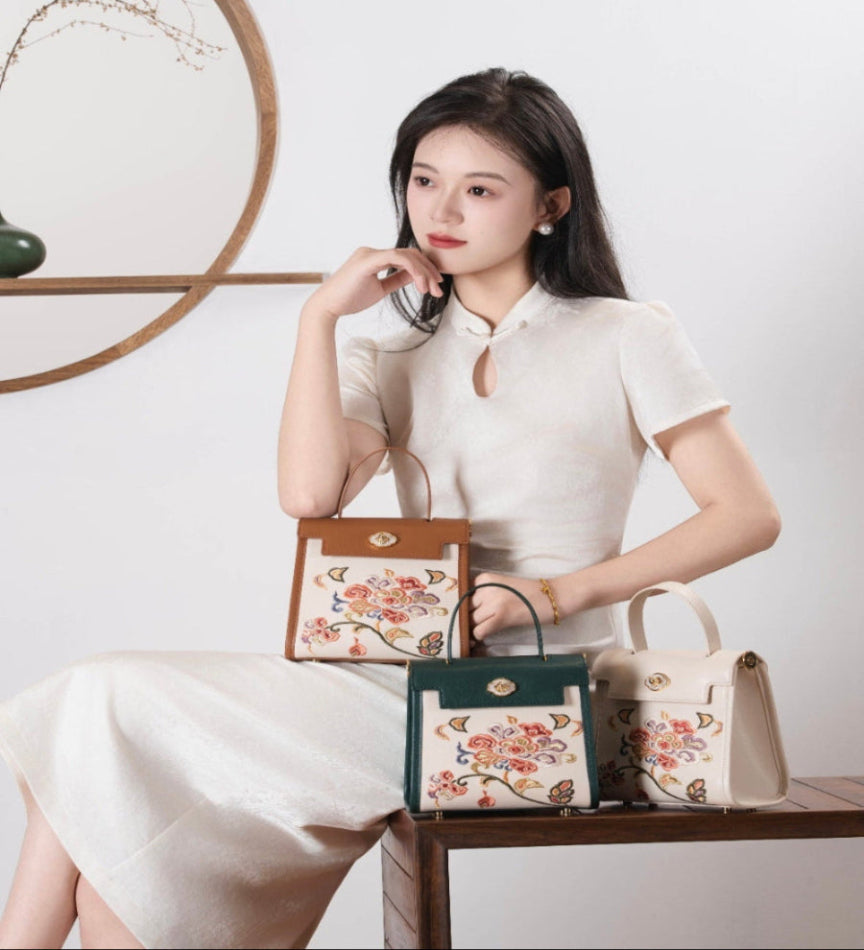 Chinese embroidered phoenix flower handbag collection with luxury Kelly bag design, heritage silk jacquard inspired structure, elegant woman wearing white dress in minimalist studio aesthetic brocade modern