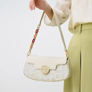 Model carrying a luxury brocade handbag on her arm, with arm slightly lifted and relaxed.