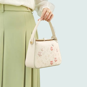 Model carrying silk handbag with single hand.