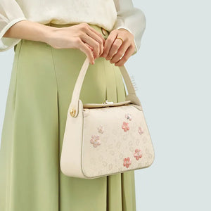 Model holding handbag with both hands at front.
