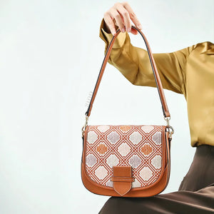 Seated model holding brocade bag on lap.