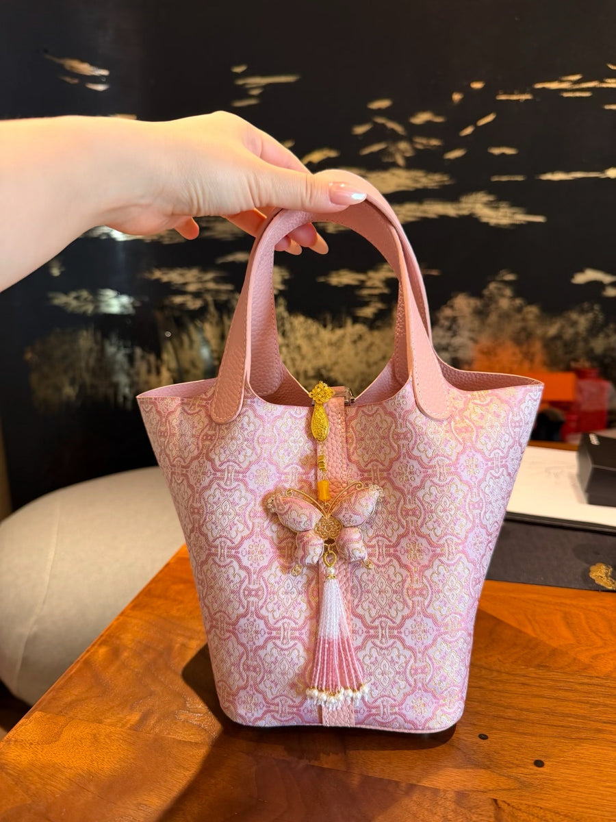 Pink Dingsheng Pattern Chinese Song Brocade handbag with blush pink leather handles, gold woven motif, and elegant decorative charm brocademodern